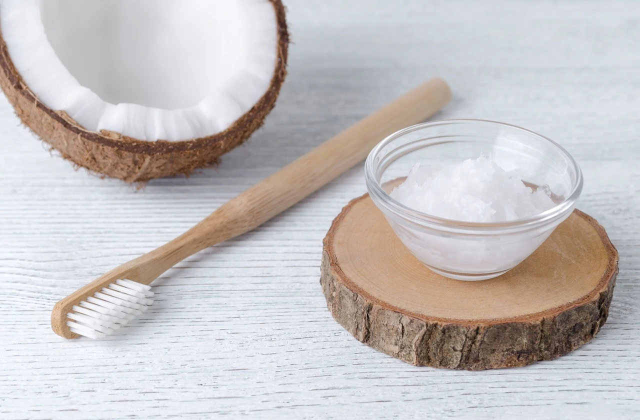A bamboo tooth brush sitting next to a bowl of coconut oil