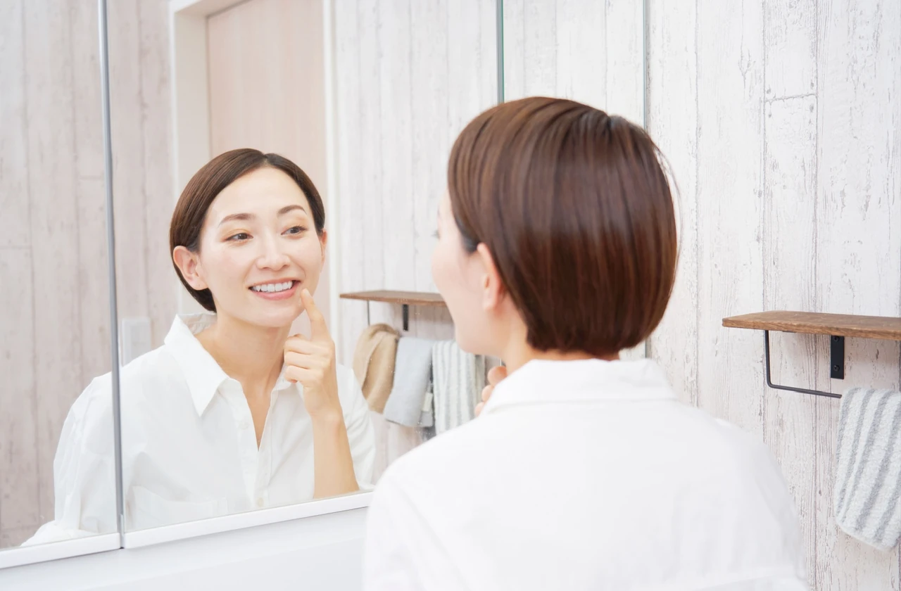 A person inspecting their teeth in the mirror.