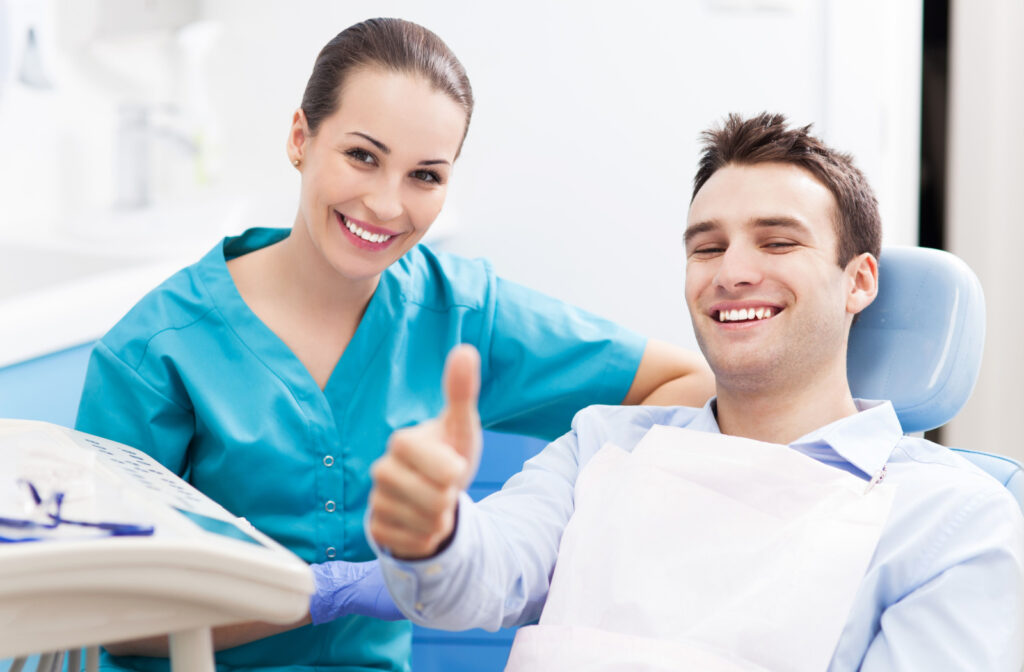 A man smiling with his female dentist, giving a thumbs up while in the dental chair
