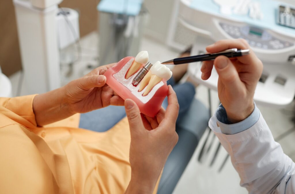 A dentist using a pen to show a patient how dental implants work while explaining how much the implant procedure will cost.