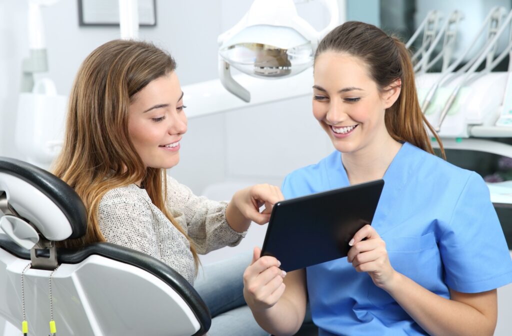 A dentist shares their patient's veneer plan using a tablet during an initial consultation.