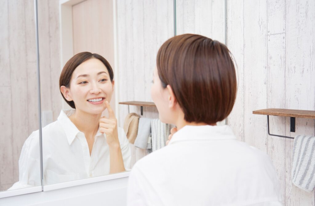 A person inspecting their teeth in the mirror.